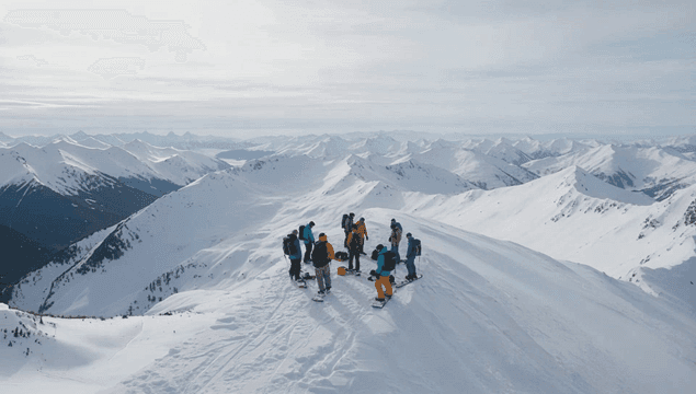 눈 덮인 산 정상 위의 스노우보드 그룹