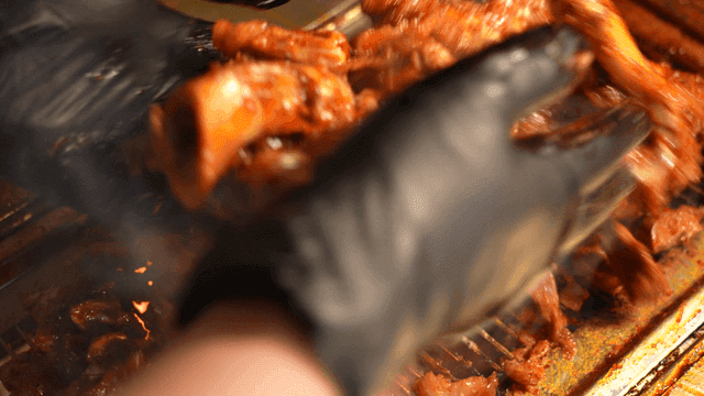Glove-clad hands mixing seasoned pig's trotters