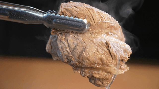 Tongs lifting steaming galbitang meat