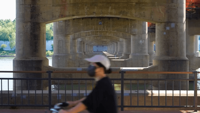 Wide river with people riding bicycles under bridge