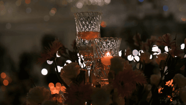 Candles glowing among flowers in dark wedding hall