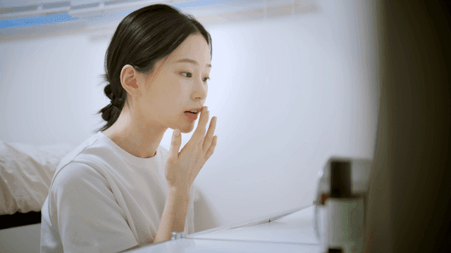 Woman applying lip balm at her vanity