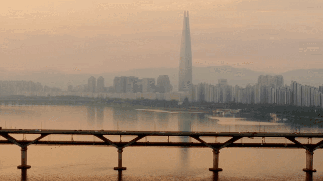 Bridge over a river with a city skyline at sunset