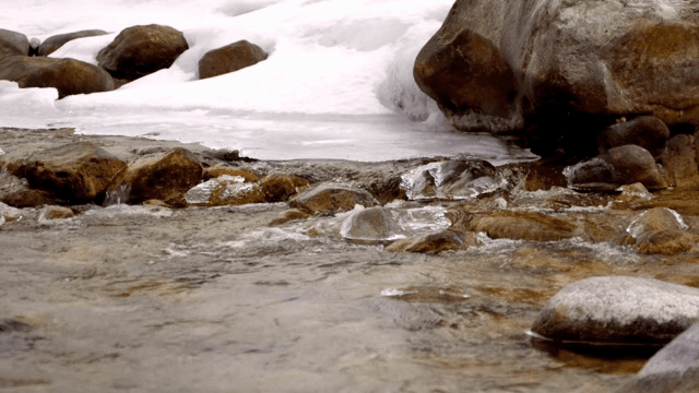 Small stream flowing through icy rocks
