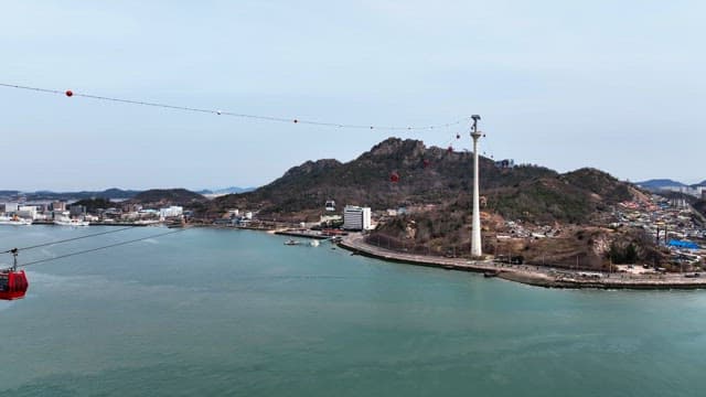 Cable cars over a coastal city with a bridge