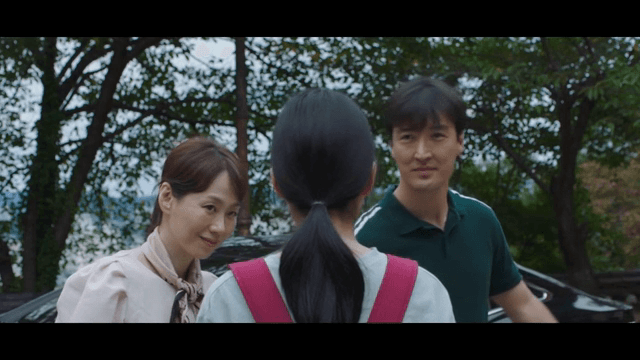 Family conversing outdoors near a car