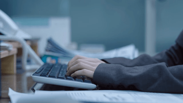 Hands typing on a keyboard in an office