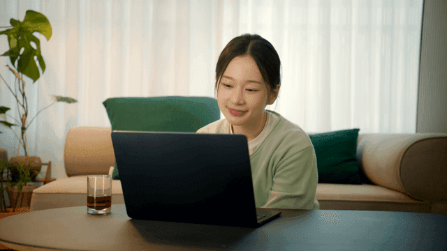 Woman smiling and looking at her laptop at home