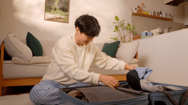 여행 가방에 옷을 싸는 젊은 남자