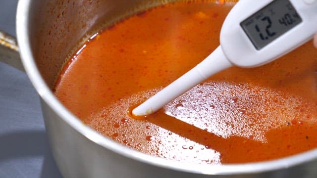 실내에서 측정기로 짬뽕의 염도를 테스트하는 손