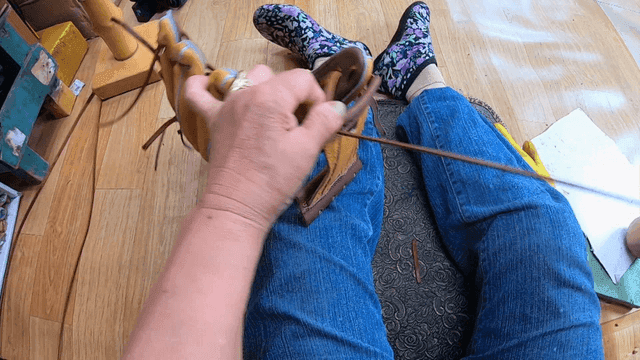 Craftsman tying lace of baseball glove by hand