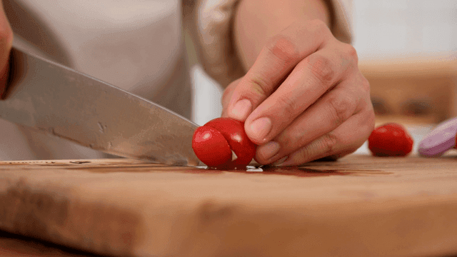 Cutting cherry tomatoes on wooden cutting board