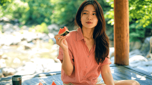 계곡가 정자 아래서 수박을 먹는 여성