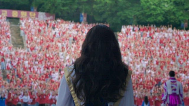 Cheering squad standing on stage during a university festivla, overlooking a cheering crowd