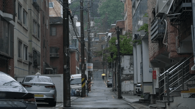 노란 우산을 든 사람이 있는 비 오는 골목