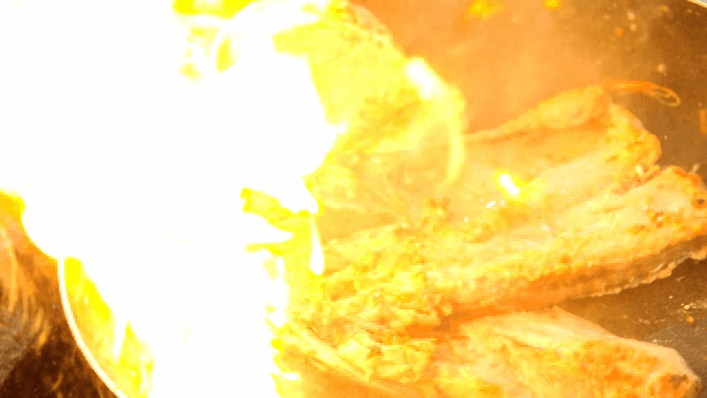 불꽃과 함께 팬에서 구워지는 명태