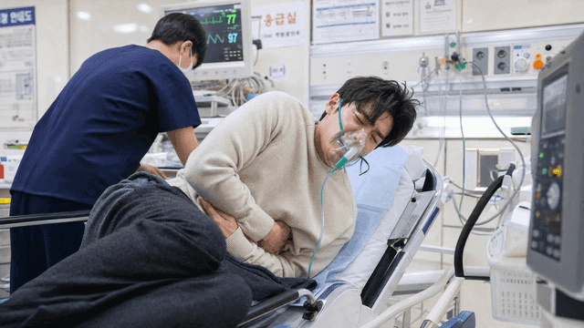 Male patient wearing oxygen mask in emergency room complaining of abdominal pain