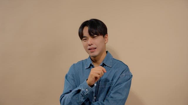 손가락을 흔들며 비웃는 데님 셔츠의 남자