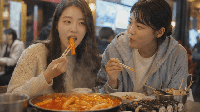 Two friends eating tteokbokki and gimbap