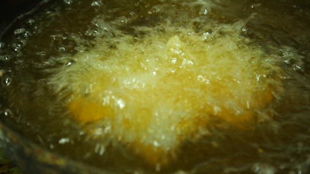 Frying pork in hot oil with tongs