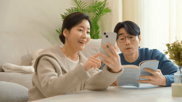 책과 휴대폰을 들고 집에서 쉬는 부부