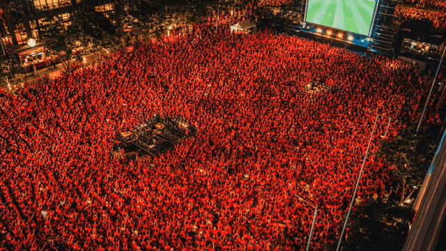 People gathered in square watching soccer match