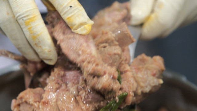 Gloved hands handling cooked meat
