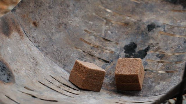 Firelighter igniting with torch on a metallic surface of a brazier