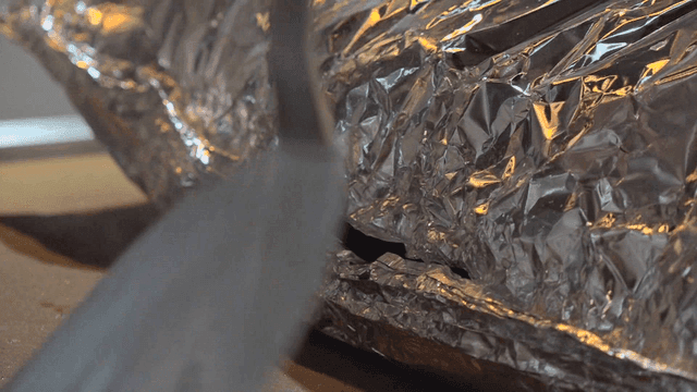Meal wrapped in steaming foil on griddle in kitchen