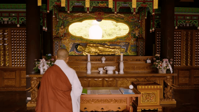Monk in a temple with a golden Buddha statue