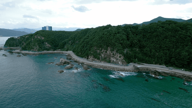 Coastal road along a lush green hillside