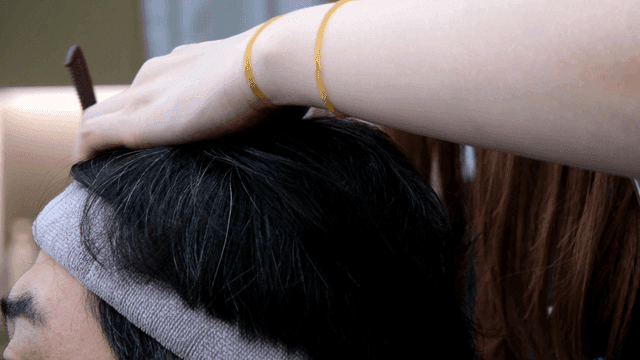 Hairdresser using comb to treat hair at beauty salon