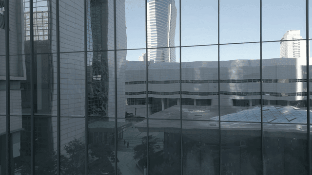 City building reflecting the urban skyline on glass exterior
