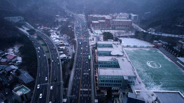 눈 내리는 도시 풍경과 차가 지나다니는 도로