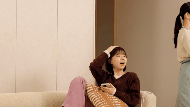 Mother slaps her daughter for looking at her smartphone on sofa.