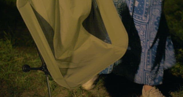 캠핑 의자를 가져와 친구 옆에 앉는 여자