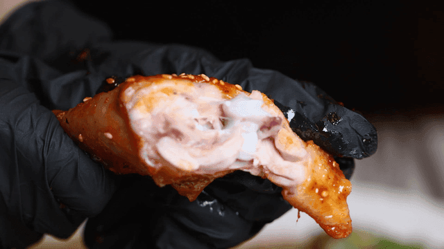 Glovenly hands tearing apart Jjimdak chicken leg