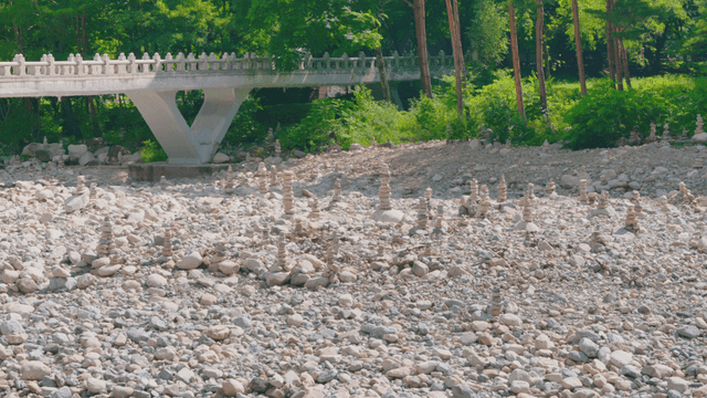 Gravel field with various stone towers against forest background