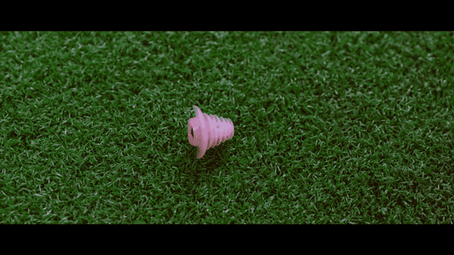 Pink earmuffs dropped on green grass