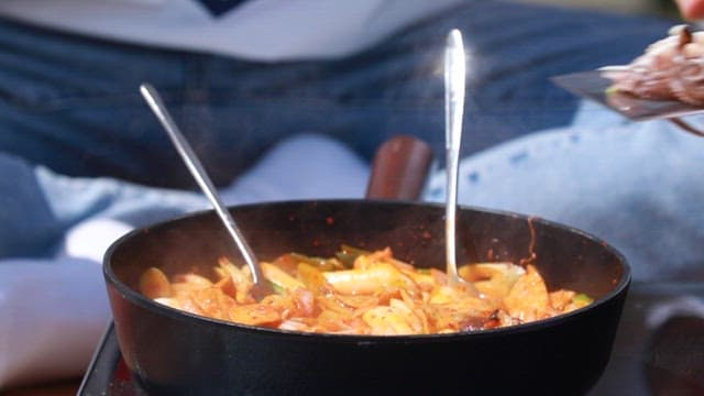 매콤한 떡볶이가 요리되는 프라이팬에 쭈꾸미를 넣는 모습