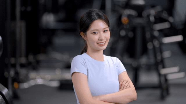 헬스장에서 자신감 있게 정면을 보고 미소 짓는 젊은 여성