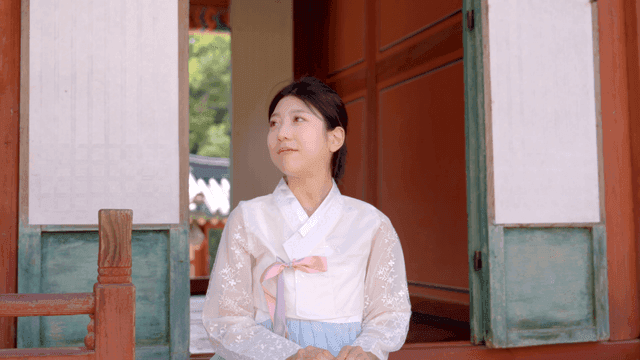 Woman in hanbok sitting at a traditional house