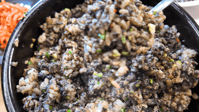 Spoon scooping out stone pot rice from earthenware pot