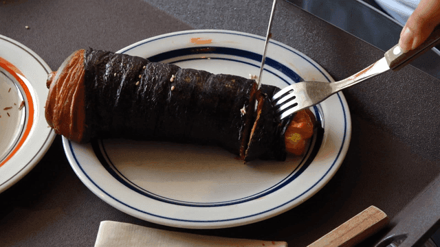 Person cutting gimbap-shaped bread on plate