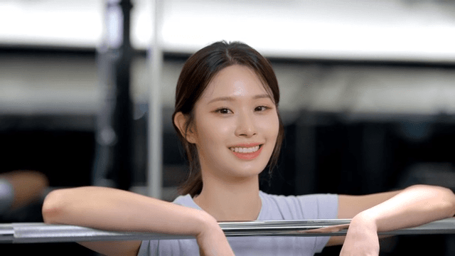 Young woman smiling while resting on a barbell at the gym