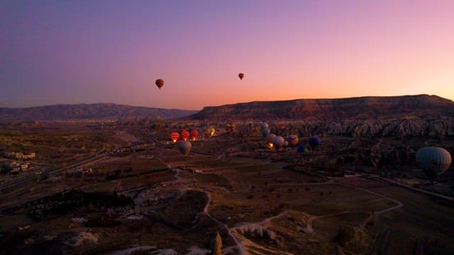 Hot Air Balloons Over Scenic Landscapes at Purple Dusk