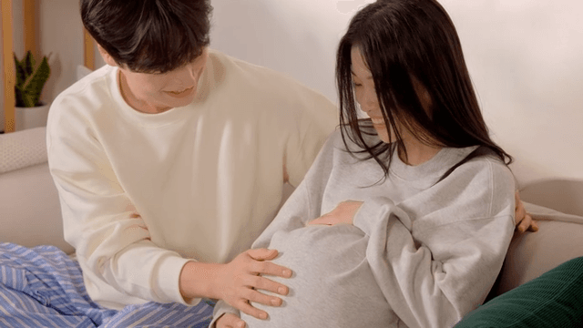 젊은 만삭 아내의 배에 귀를 대보는 젊은 남편