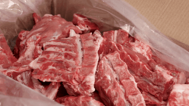 Raw pork backbone pieces in cardboard box