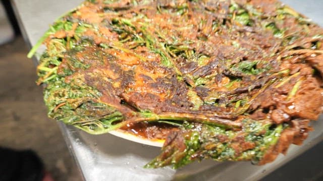 Plate of Korean pancake being cut and dipped in sauce