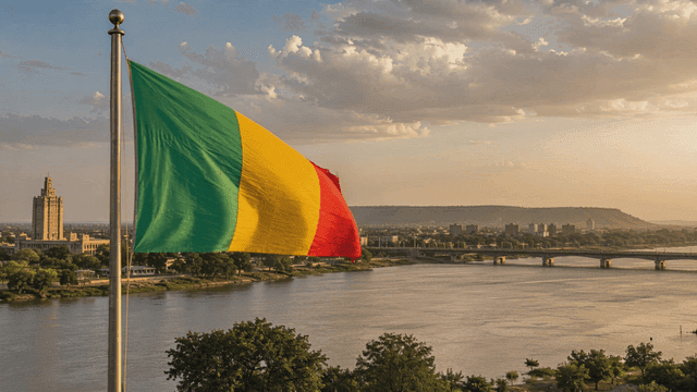 A flag waving by a riverside cityscape